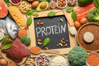 Photo of Chalkboard with written word Protein among natural food, top view