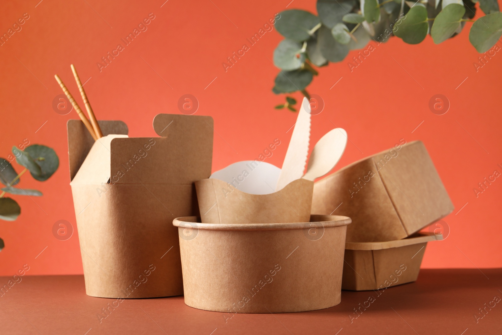 Photo of Eco friendly food packaging. Paper containers, tableware and eucalyptus branches on color background