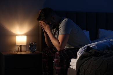 Photo of Man covering face with hands on bed