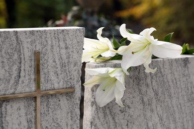 Photo of White lilies on granite tombstone outdoors. Funeral ceremony