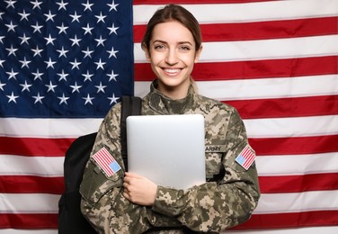 Photo of Female cadet with backpack and laptop against American flag. Military education
