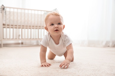 Photo of Cute little baby crawling on carpet indoors