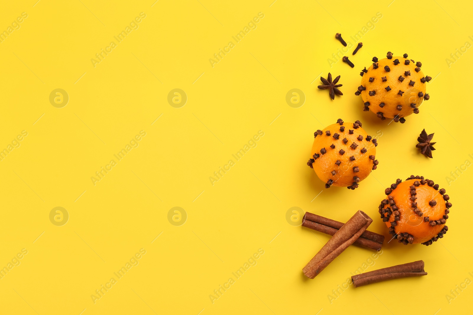 Photo of Flat lay composition with pomander balls made of fresh tangerines on yellow background. Space for text