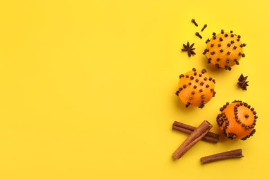 Flat lay composition with pomander balls made of fresh tangerines on yellow background. Space for text