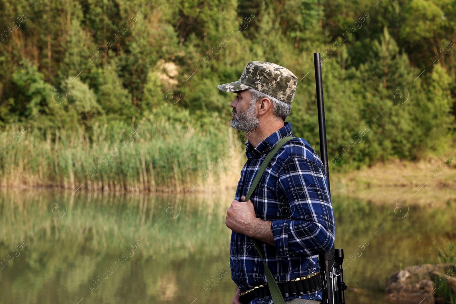 Photo of Man with hunting rifle near lake outdoors. Space for text