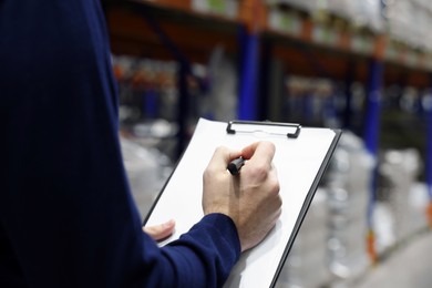 Photo of Manager writing in clipboard at warehouse, closeup