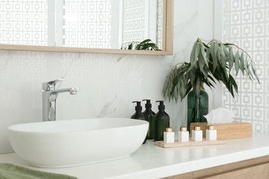 Bathroom counter with stylish vessel sink and toiletries. Interior design