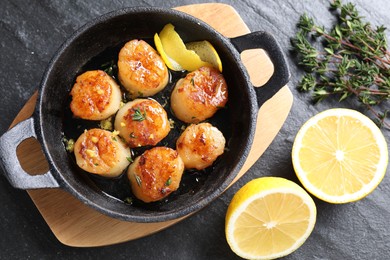 Photo of Delicious fried scallops and ingredients on dark gray textured table, flat lay