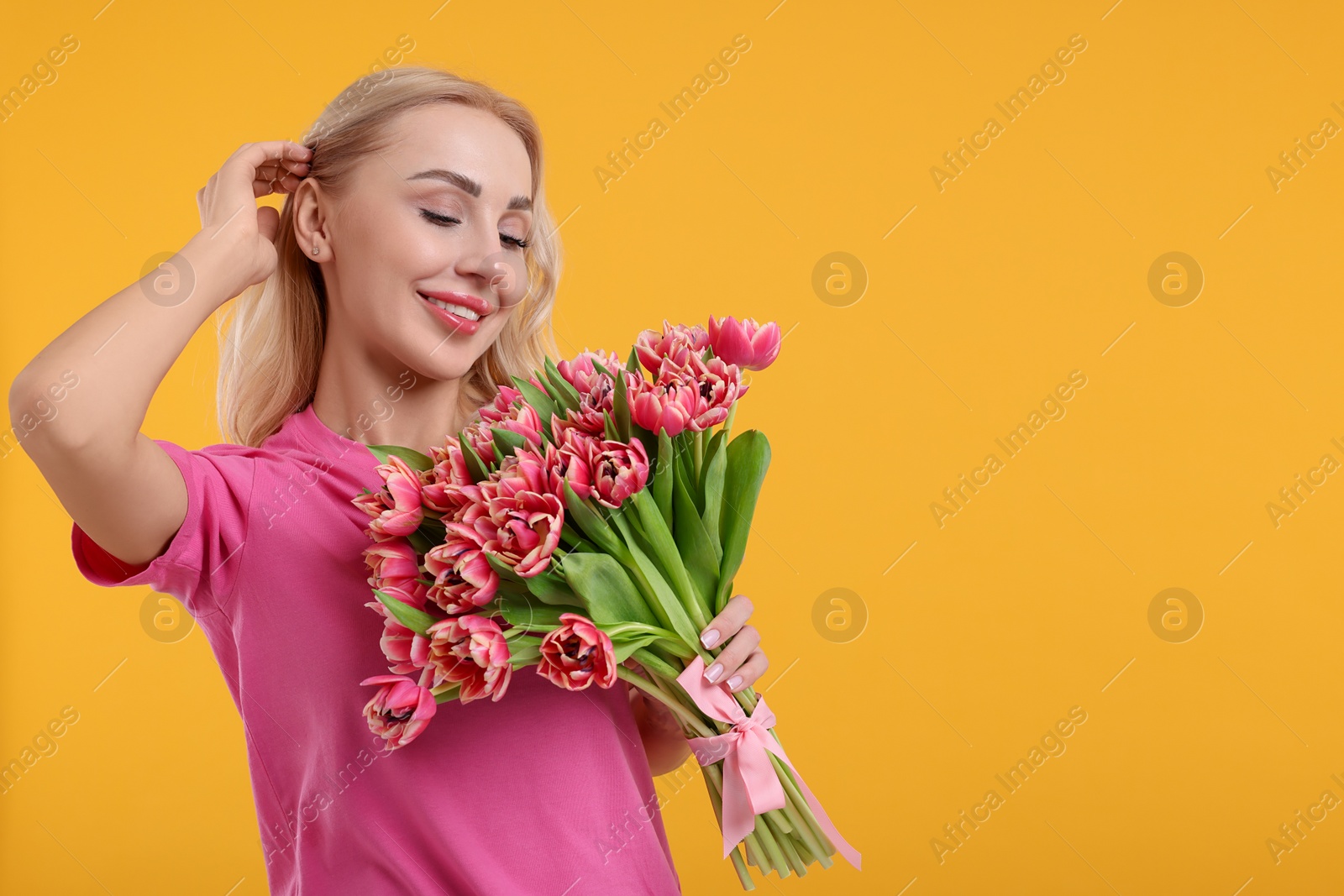 Photo of Happy young woman with beautiful bouquet on orange background. Space for text