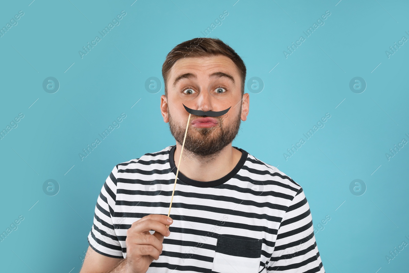Photo of Funny man with fake mustache on turquoise background