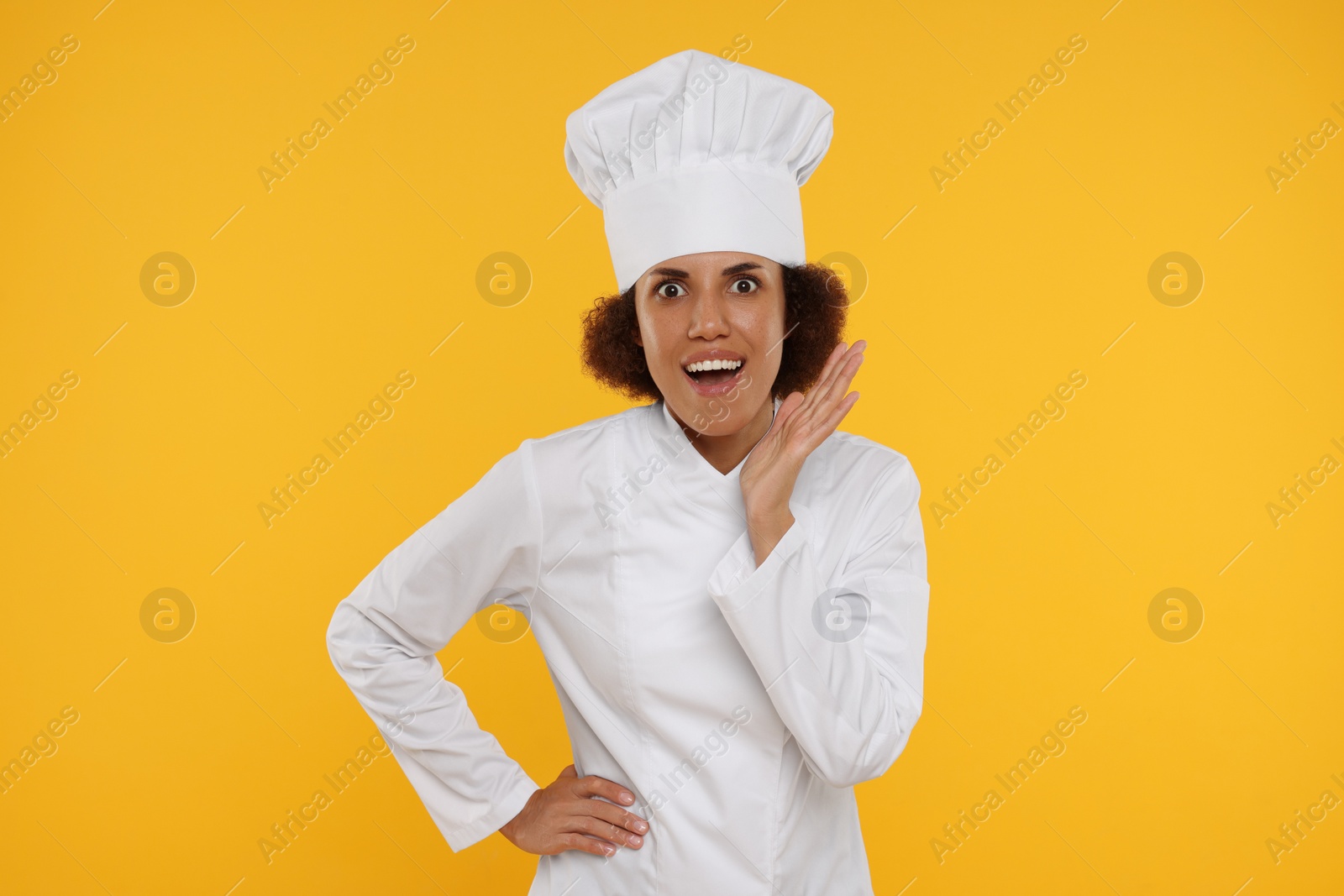 Photo of Portrait of emotional female chef in uniform on orange background