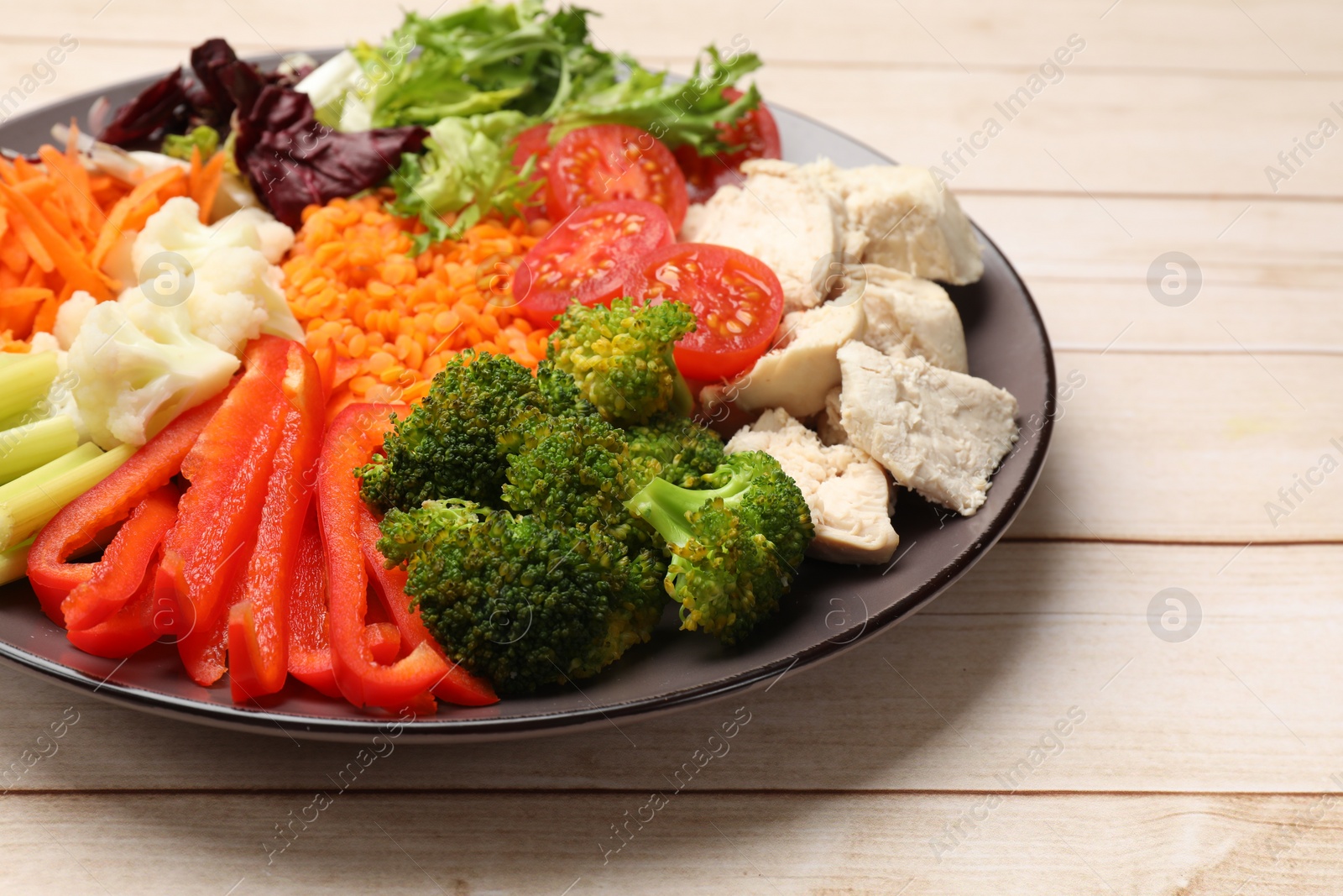 Photo of Balanced diet and healthy foods. Plate with different delicious products on light wooden table, closeup