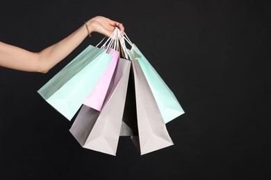 Photo of Woman holding shopping bags on black background, closeup. Big sale