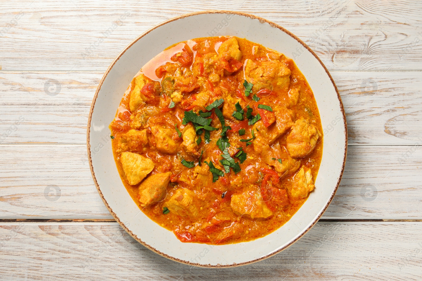 Photo of Delicious chicken curry on wooden table, top view