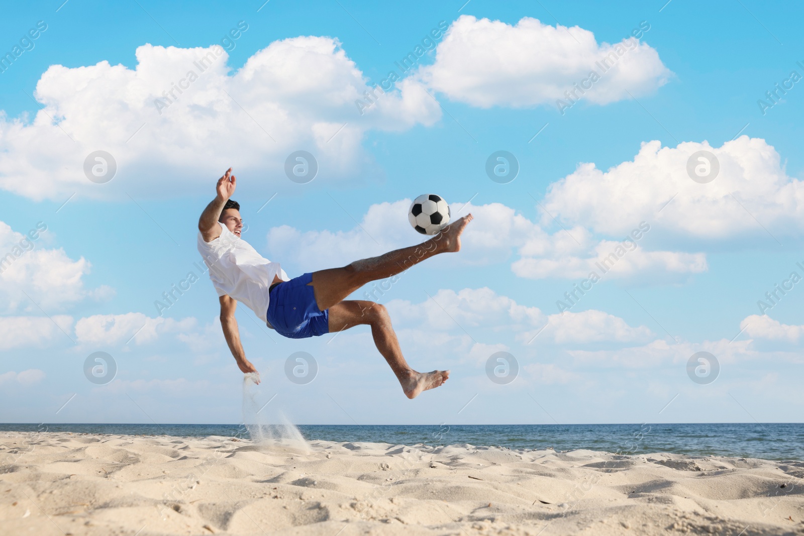 Photo of Man kicking football ball on beach near sea