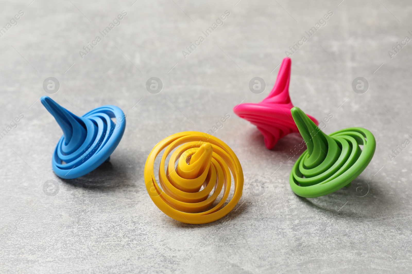 Photo of Bright spinning tops on grey textured background, closeup