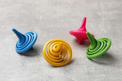 Photo of Bright spinning tops on grey textured background, closeup