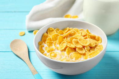 Photo of Tasty crispy corn flakes with milk on light blue wooden  table