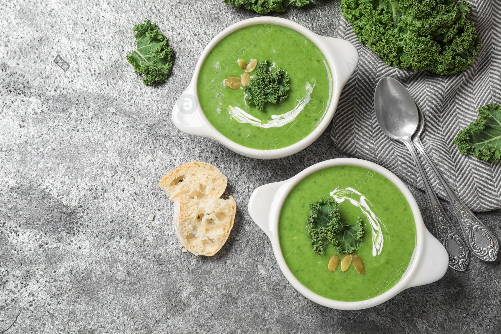 Photo of Tasty kale soup served on grey table, flat lay
