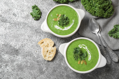 Tasty kale soup served on grey table, flat lay