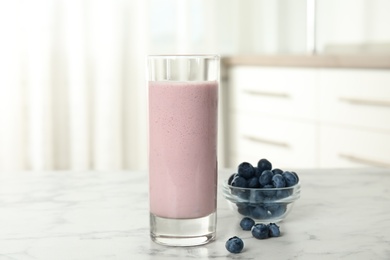 Tasty milk shake and blueberries on white marble table