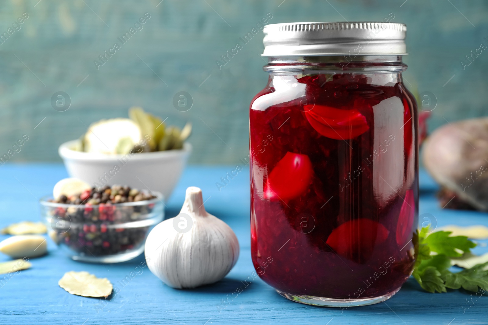 Photo of Pickled beets in glass jar on light blue wooden table