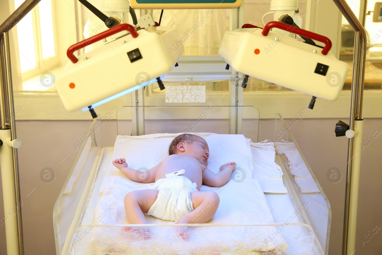 Photo of Newborn child under ultraviolet lamps in hospital