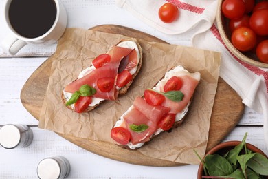 Photo of Flat lay composition of tasty bruschettas with prosciutto and ingredients on white wooden table
