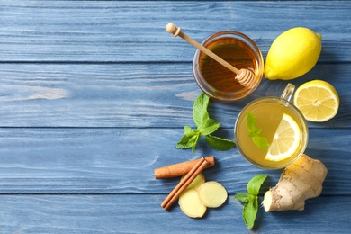 Cup with hot tea, lemon and ginger for cold on wooden table, top view