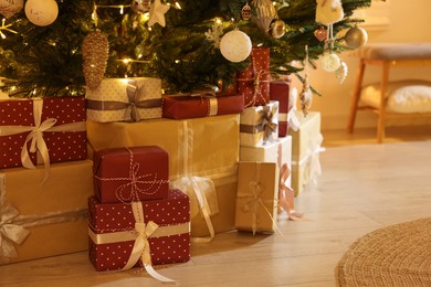 Photo of Many gift boxes under decorated Christmas tree indoors, closeup