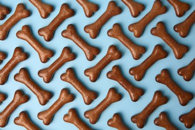 Flat lay composition with bone shaped dog cookies on light blue background