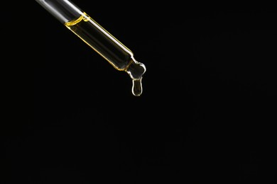 Photo of Dripping tincture from pipette on black background, closeup. Space for text