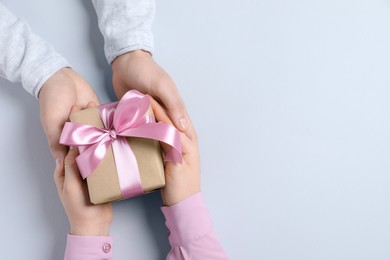 Photo of Man giving gift box to woman on light gray background, top view. Space for text
