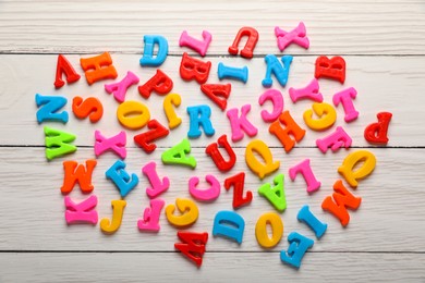 Photo of Colorful magnetic letters on white wooden table, flat lay