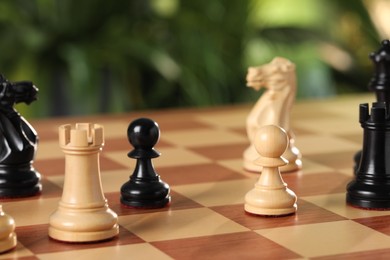 Photo of Wooden pieces on chess board against blurred background, closeup
