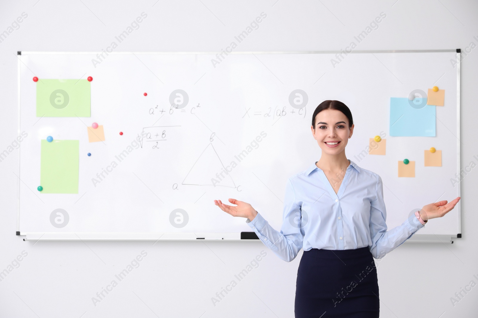 Photo of Young teacher near whiteboard in modern classroom. Space for text