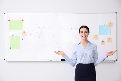 Photo of Young teacher near whiteboard in modern classroom. Space for text