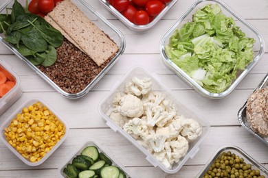 Photo of Glass and plastic containers with different fresh products on white wooden table, flat lay