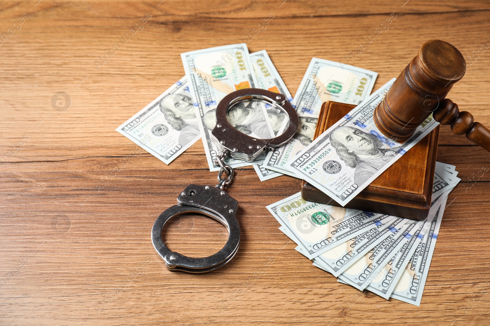 Photo of Judge's gavel, money and handcuffs on wooden table