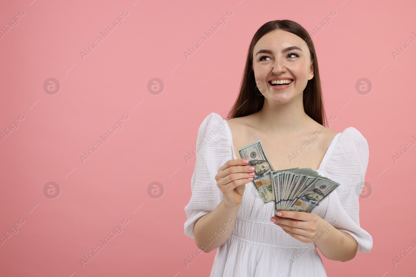 Photo of Happy woman with dollar banknotes on pink background, space for text