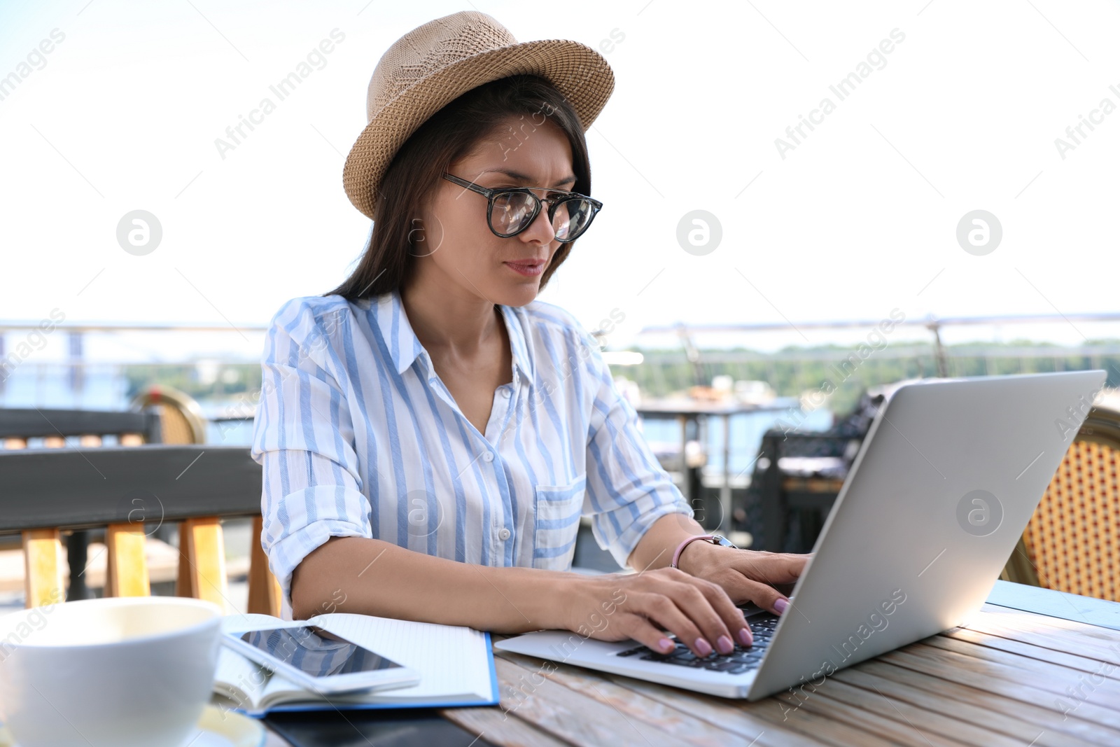 Photo of Beautiful woman with glasses using laptop at outdoor cafe