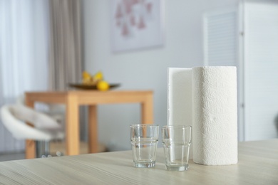 Photo of Roll of paper towels and glasses on table indoors. Space for text