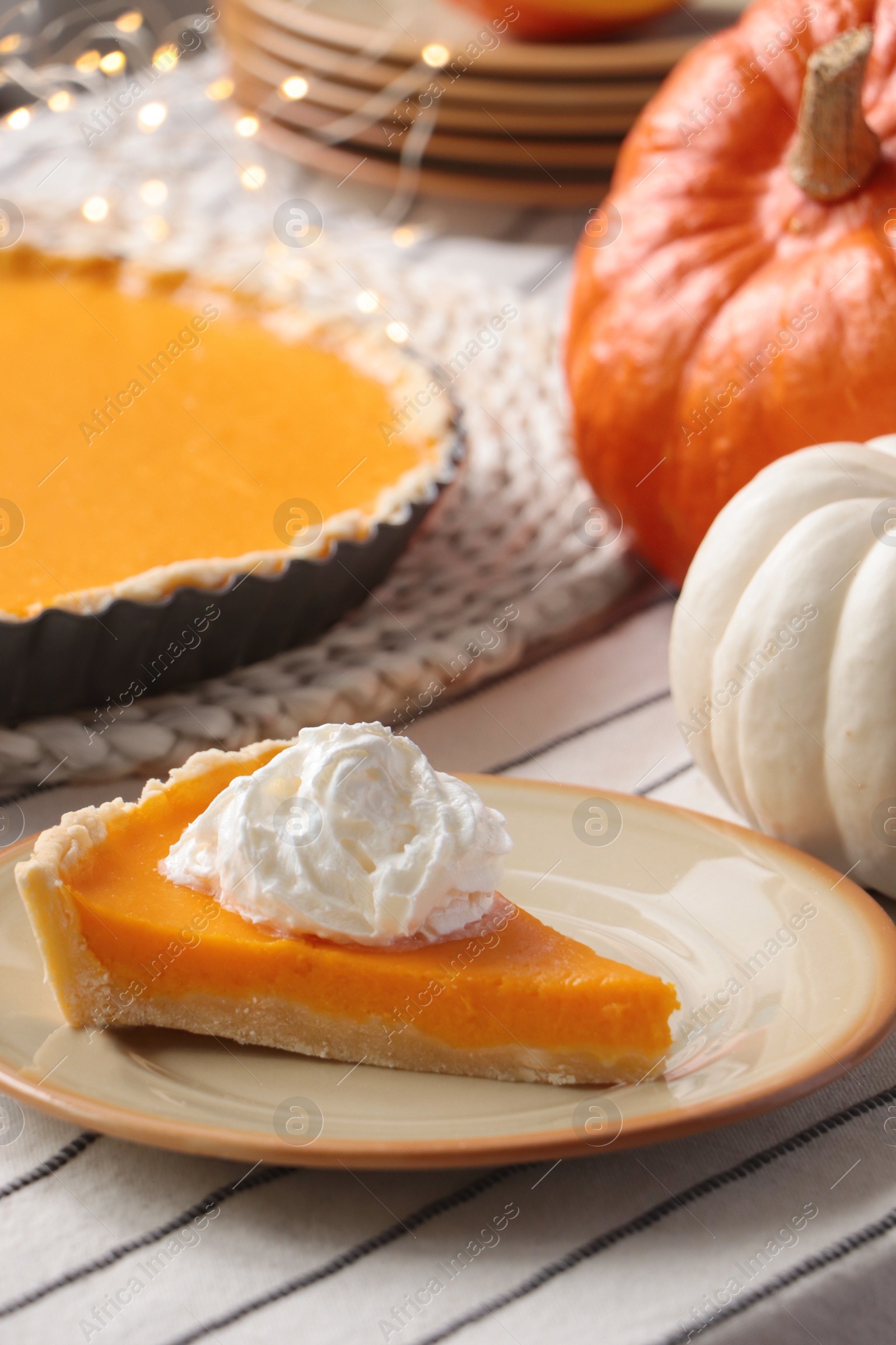 Photo of Piece of fresh homemade pumpkin pie with whipped cream on table