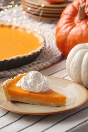 Photo of Piece of fresh homemade pumpkin pie with whipped cream on table