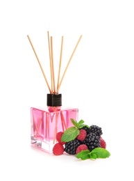 Photo of Aromatic reed air freshener and berries on white background