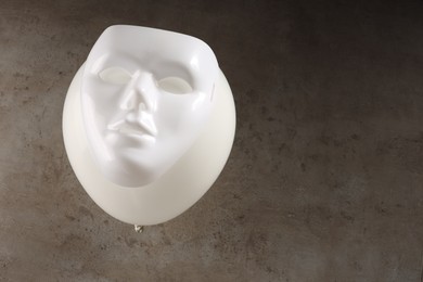Photo of Theatrical performance. Plastic mask and white balloon on grey table, above view. Space for text