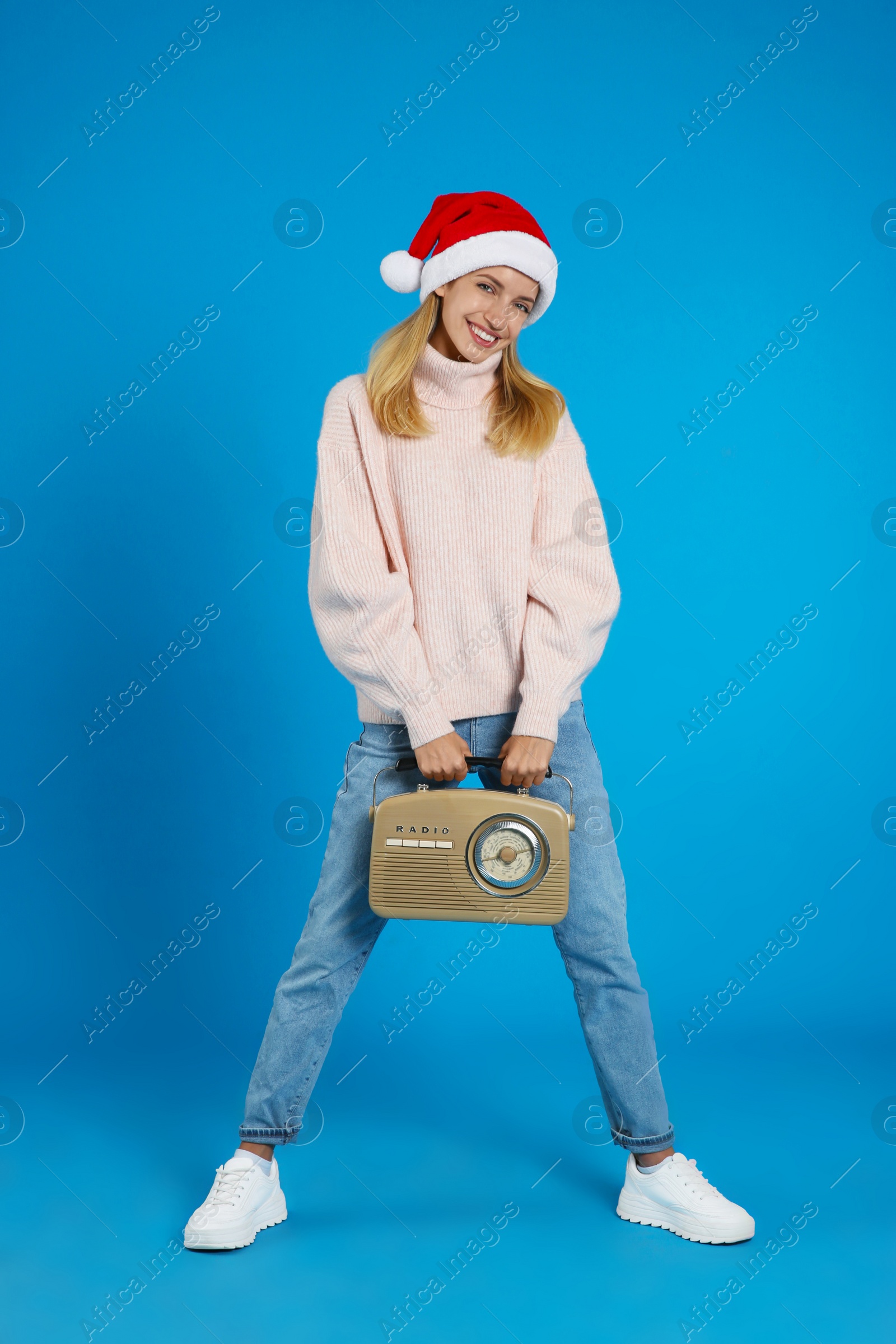 Photo of Happy woman with vintage radio on blue background. Christmas music