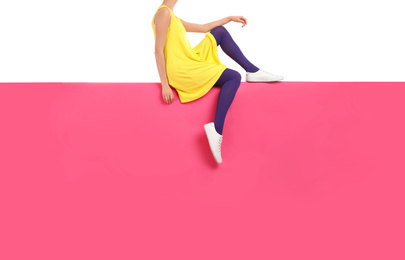 Woman wearing purple tights and stylish shoes sitting on color background, closeup