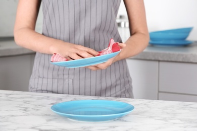 Photo of Woman wiping plate with towel in kitchen, closeup