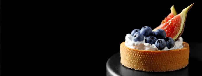 Image of Delicious tartlet with fresh blueberries and figs on cake stand against black background, space for text. Banner design